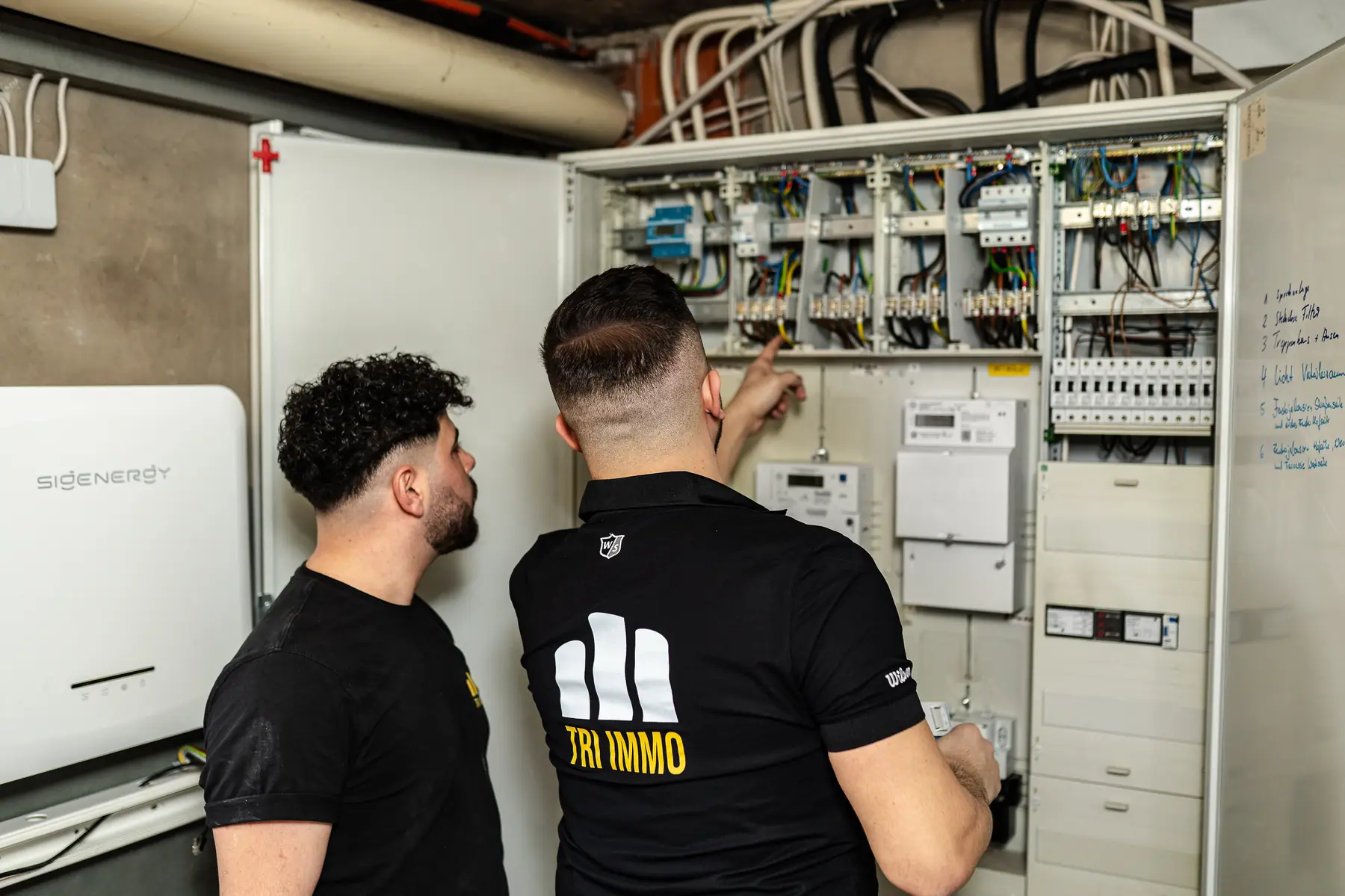 Zwei Mitarbeiter des Energiewerks besprechen sich an einem geöffneten Zählerschrank