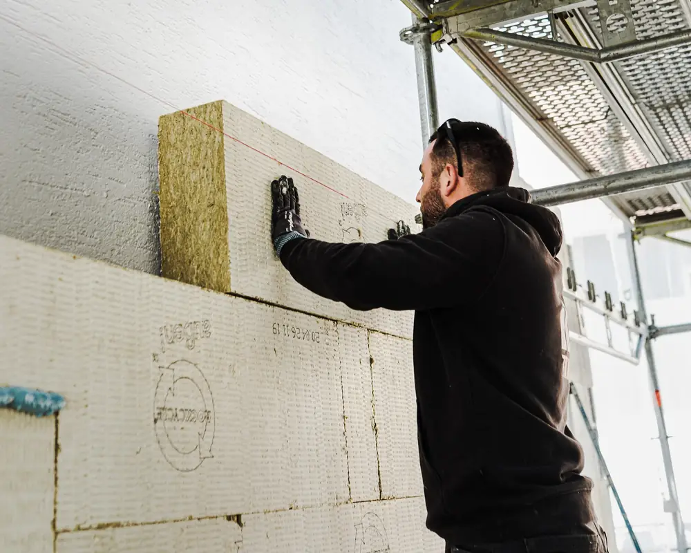 Monteur setzt in Bruchsal eine Dämmplatte aus Mineralwolle an die Fassade