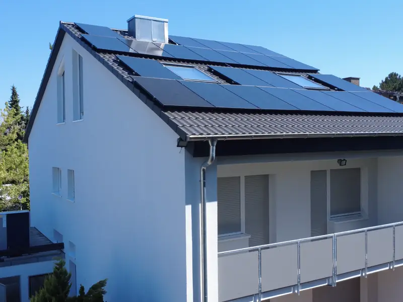 Saniertes Haus mit weißer, gedämmter Fassade, neuem dunklem Dach und Photovoltaikmodulen
