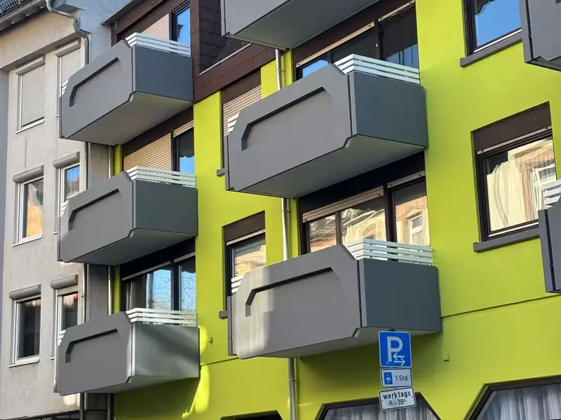 Mehrfamilienhaus in Mannheim mit neu gestrichener Fassade in Grün und Grau und sanierten Balkonen