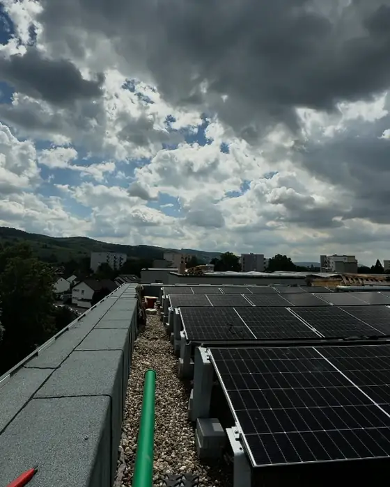 Photovoltaikmodule auf dem Flachdach eines Mehrfamilienhauses in Heppenheim, darüber Wolken