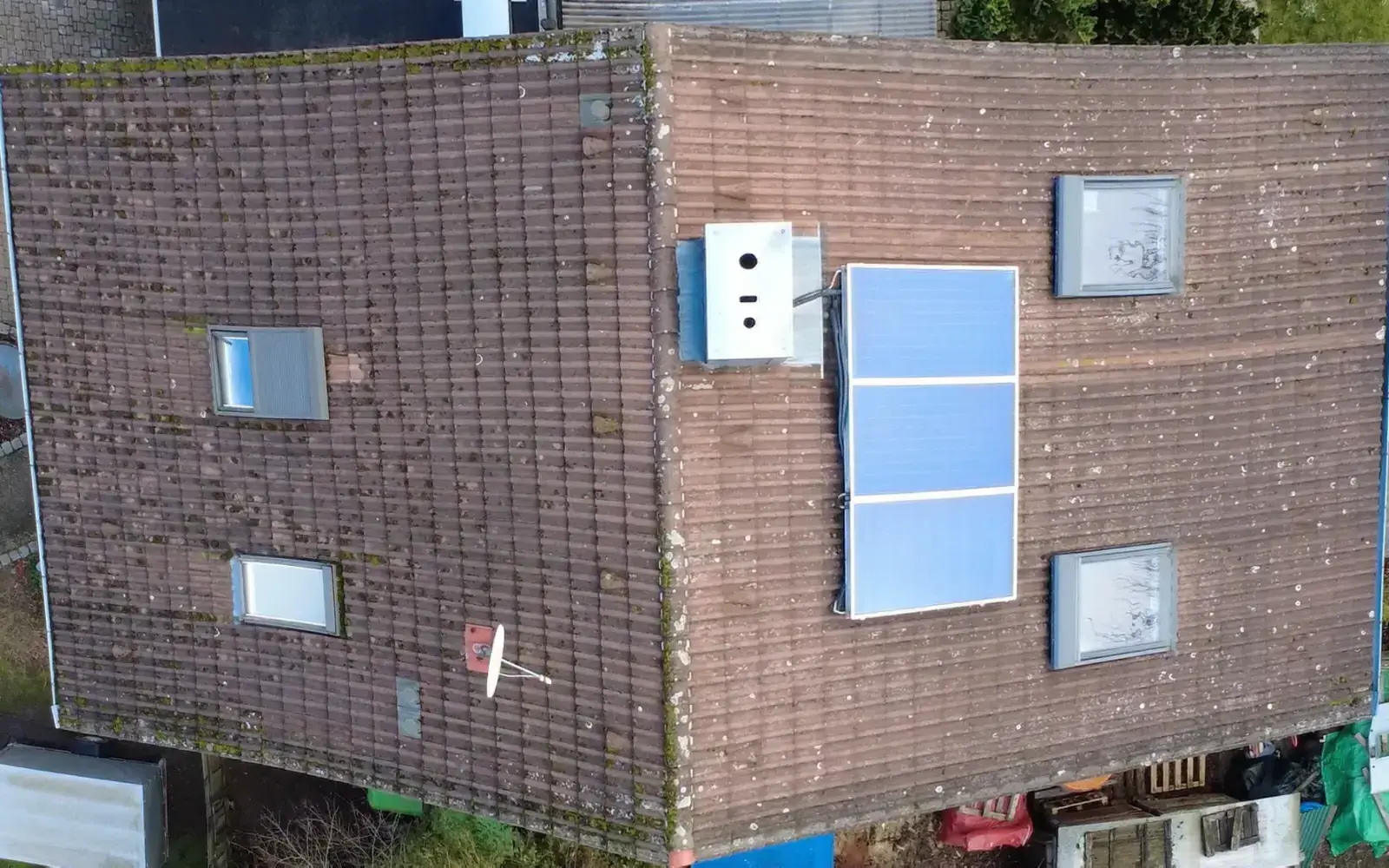 Dach von oben vor der Sanierung: alte, vermooste Eindeckung mit Solarkollektoren und vier alten Dachfenstern
