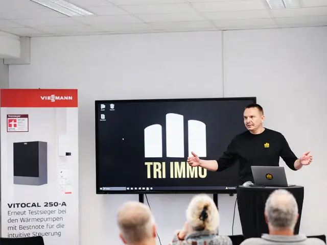 Geschäftsführer Eduard Missal spricht beim Infoabend von TRI IMMO vor Gästen, daneben ein Aufsteller von Viessmann
