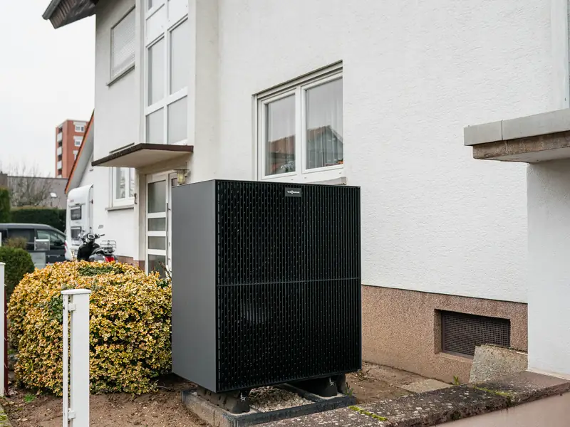 Außengerät einer neuen Wärmepumpe von Viessmann neben einem weißen Wohnhaus
