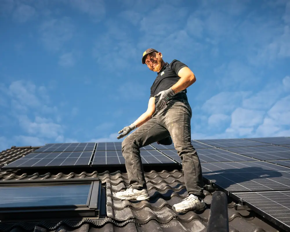 Dachdecker auf einem frisch gedeckten Dach in Heidelberg, daneben Photovoltaikmodule