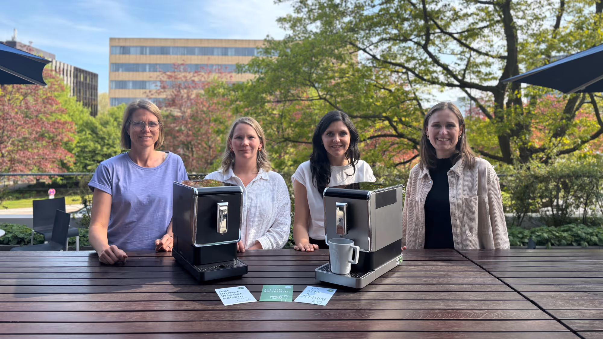 Andrea Schneller from koorvi with Tchibo’s Kristina Kölling and Karoline Reperich standing beside refurbished Tchibo Esperto Caffè coffee machines