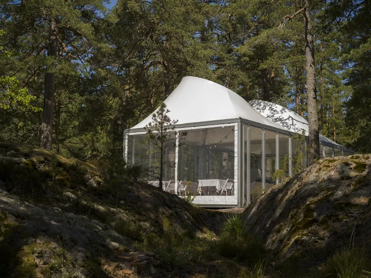 Ett tält av modellen vulkan, med transparent tak, monterat på en mässa, med fåtöljer och inredning i dom.