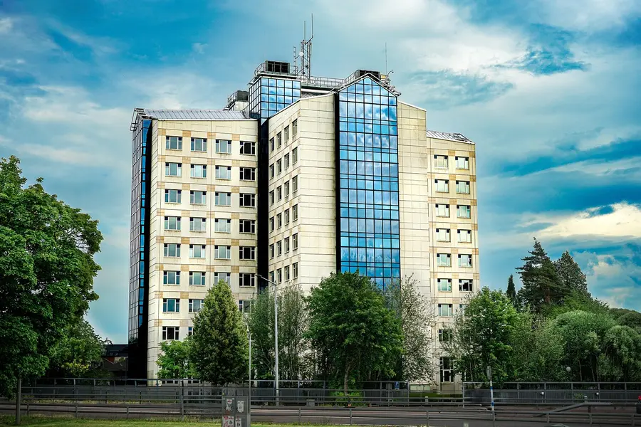 Vy över Borlänge centrum med spegelblank damm och höstträd i förgrunden.