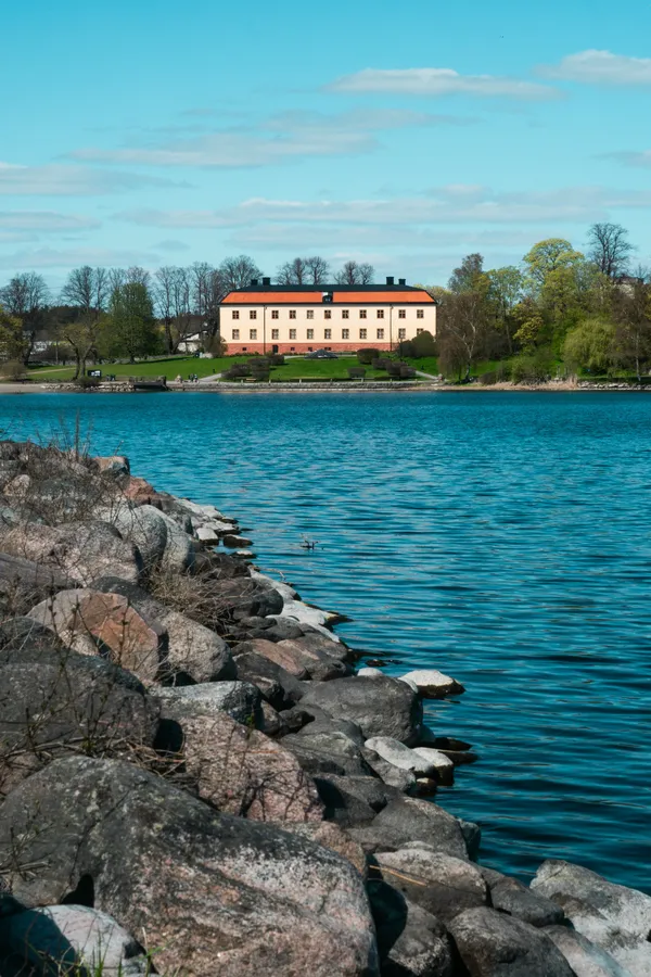 Solnedgång över Sollentuna med vatten och stadens bebyggelse i bakgrunden.