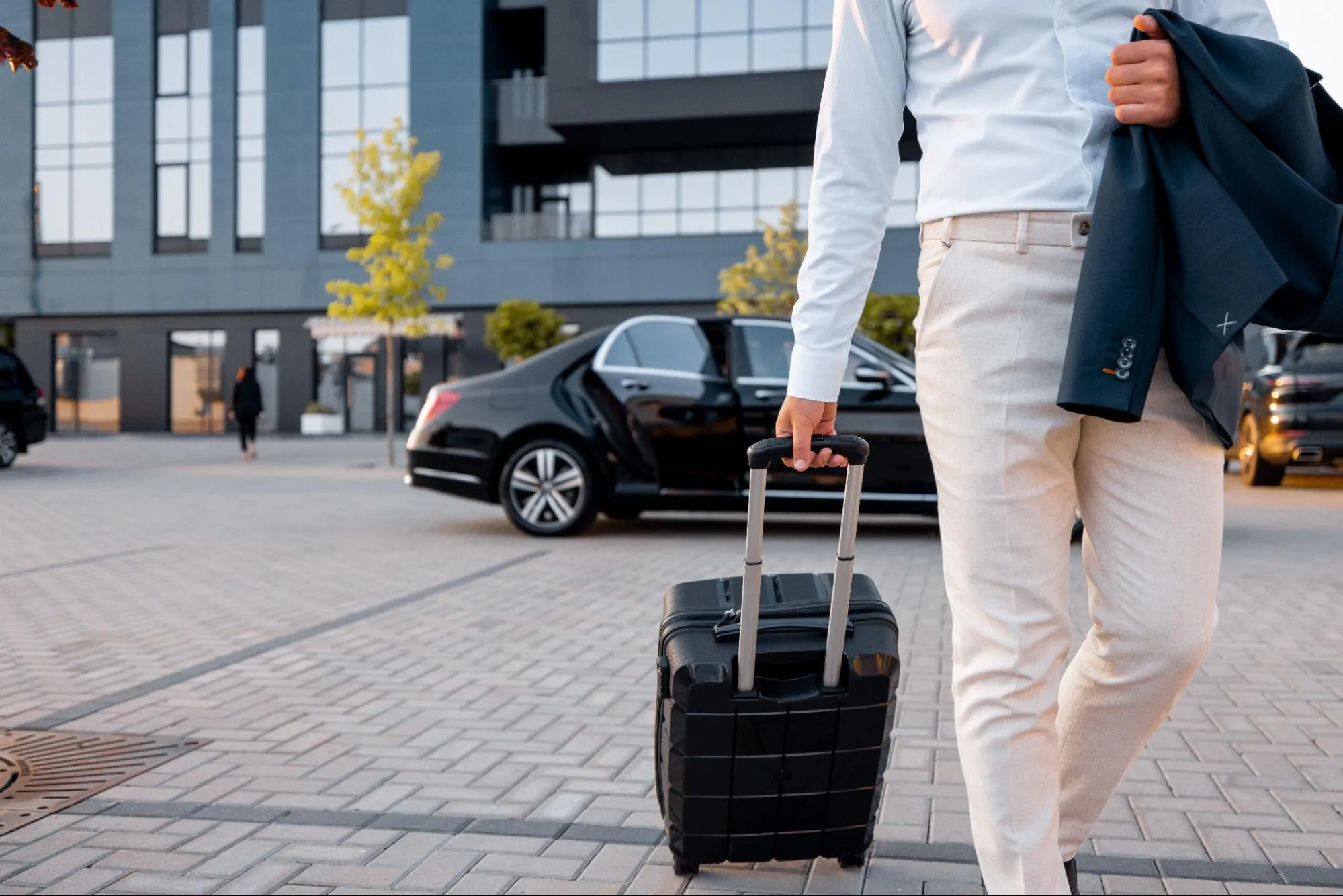 Business traveler with suitcase arriving at hotel with luxury car service