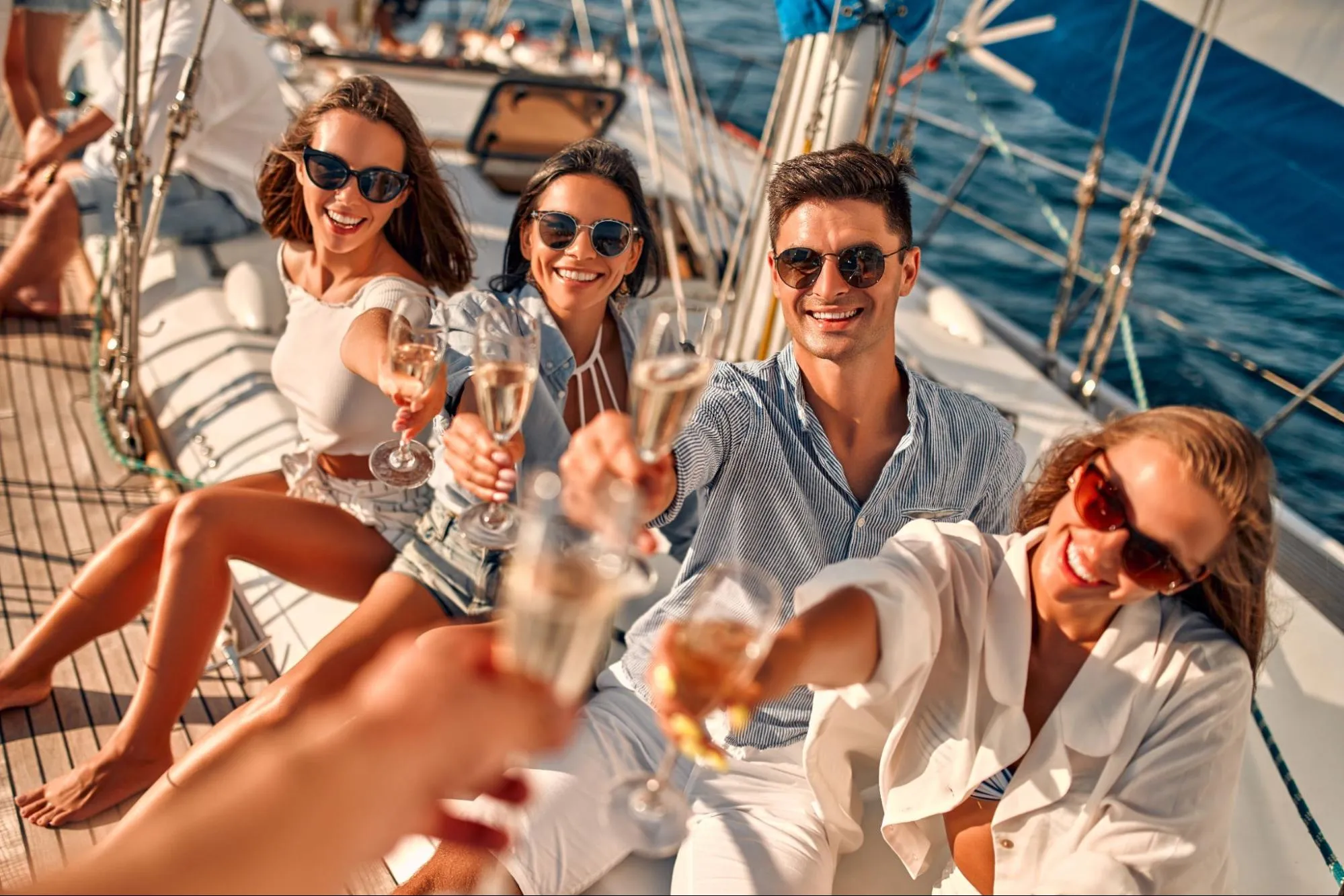 Smiling friends raising champagne glasses on luxury yacht during summer boat party