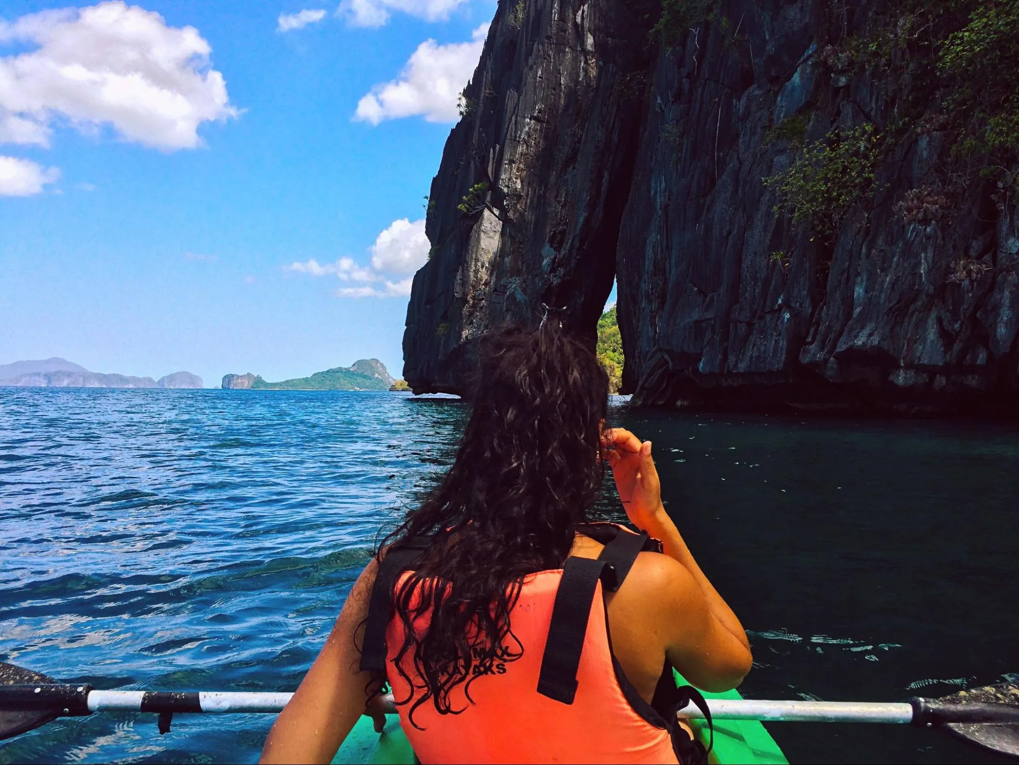 Woman kayaking through tropical cliffs and turquoise sea on adventure travel trip