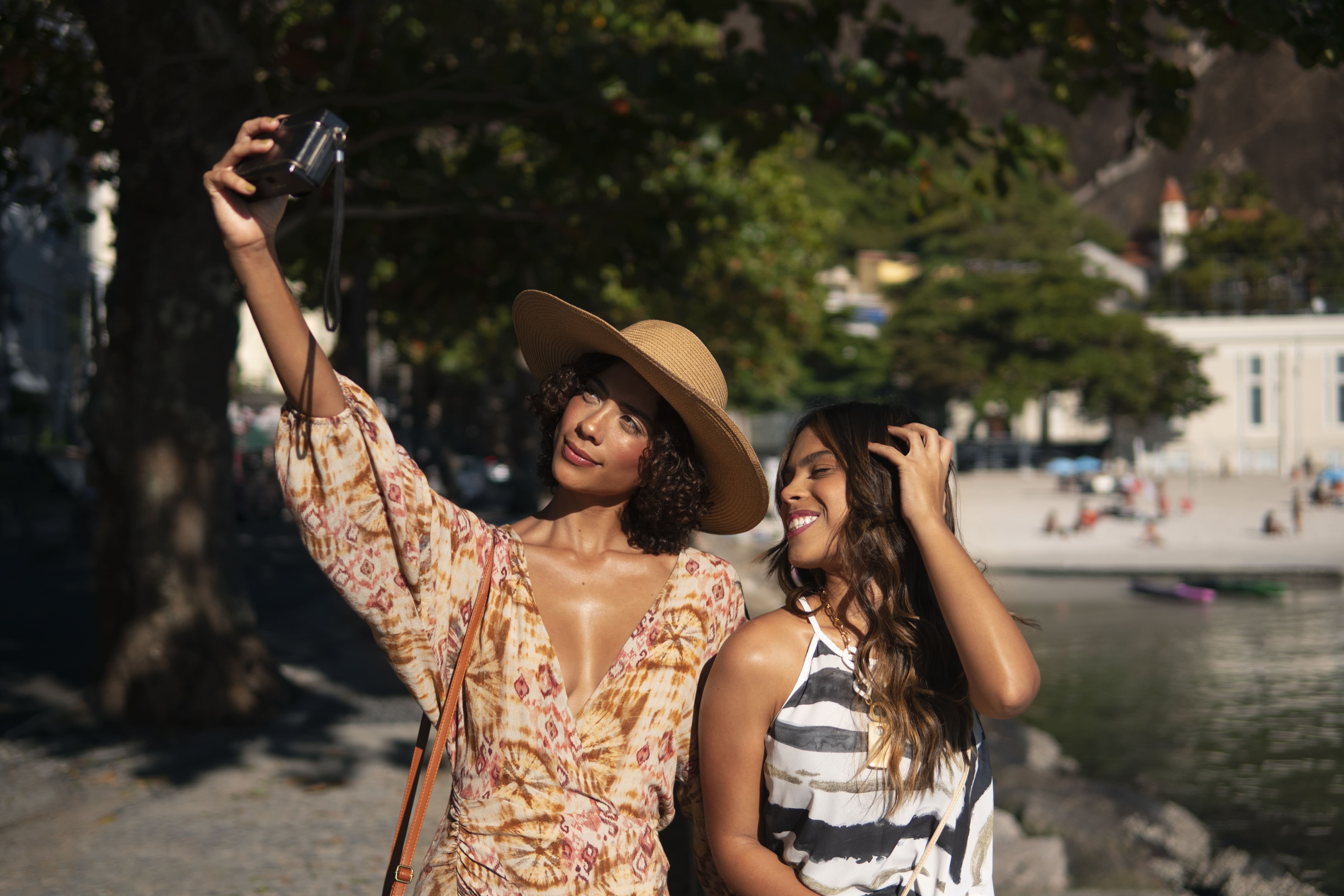 Two women in stylish summer outfits taking a selfie together outdoors near the beach in the Dominican Republic.