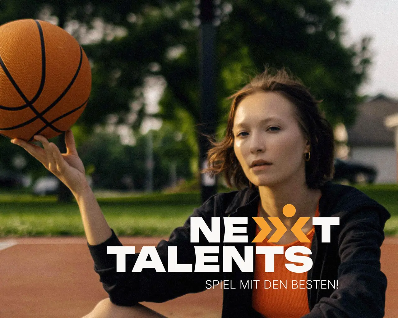 Eine jugendliche hält lässig einen Basketball, das Logo Nexxt Talents ist zu sehen