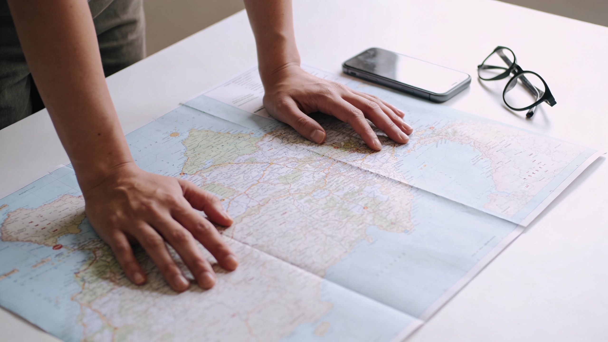 A person leans over a map spread out on a table during a lunch break planning session.