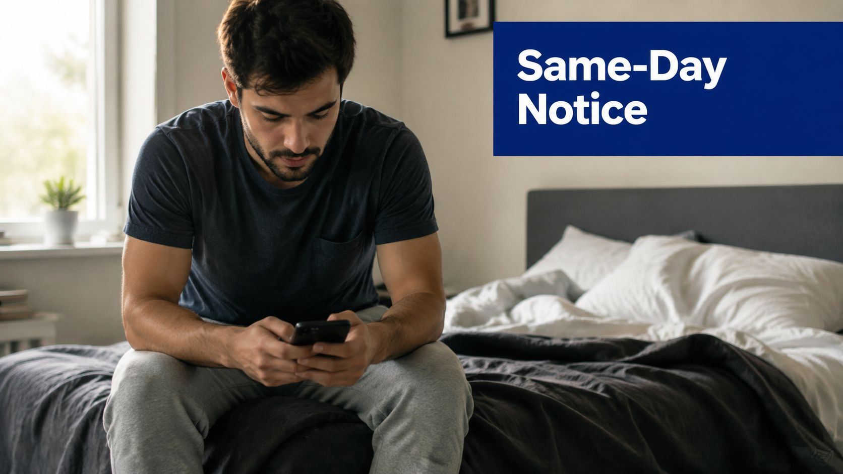 A young man sitting on his bed looking at his smartphone with a serious, concerned facial expression.