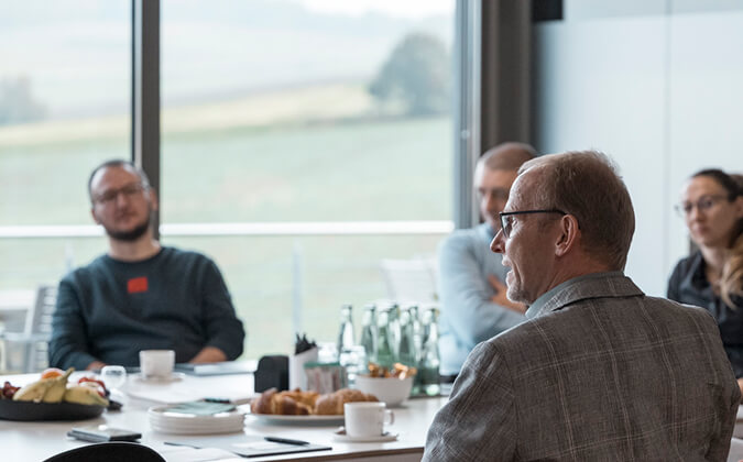Mehrere Workshop-Teilnehmer sitzen gemeinsam im Bergwerk-Besprechungsraum. Auf dem Tisch stehen Gebäck und Getränke.