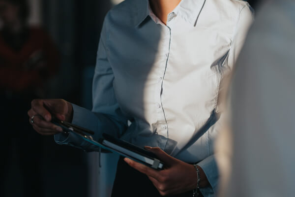 Ein Lichtstrahl fällt auf zwei Personen in einer geschäftlichen Gesprächssituation. Eine Person hält ein Klemmbrett und einen Stift in der Hand. Der Moment wirkt wie eine wichtige Entscheidung im Kundenkontakt.
