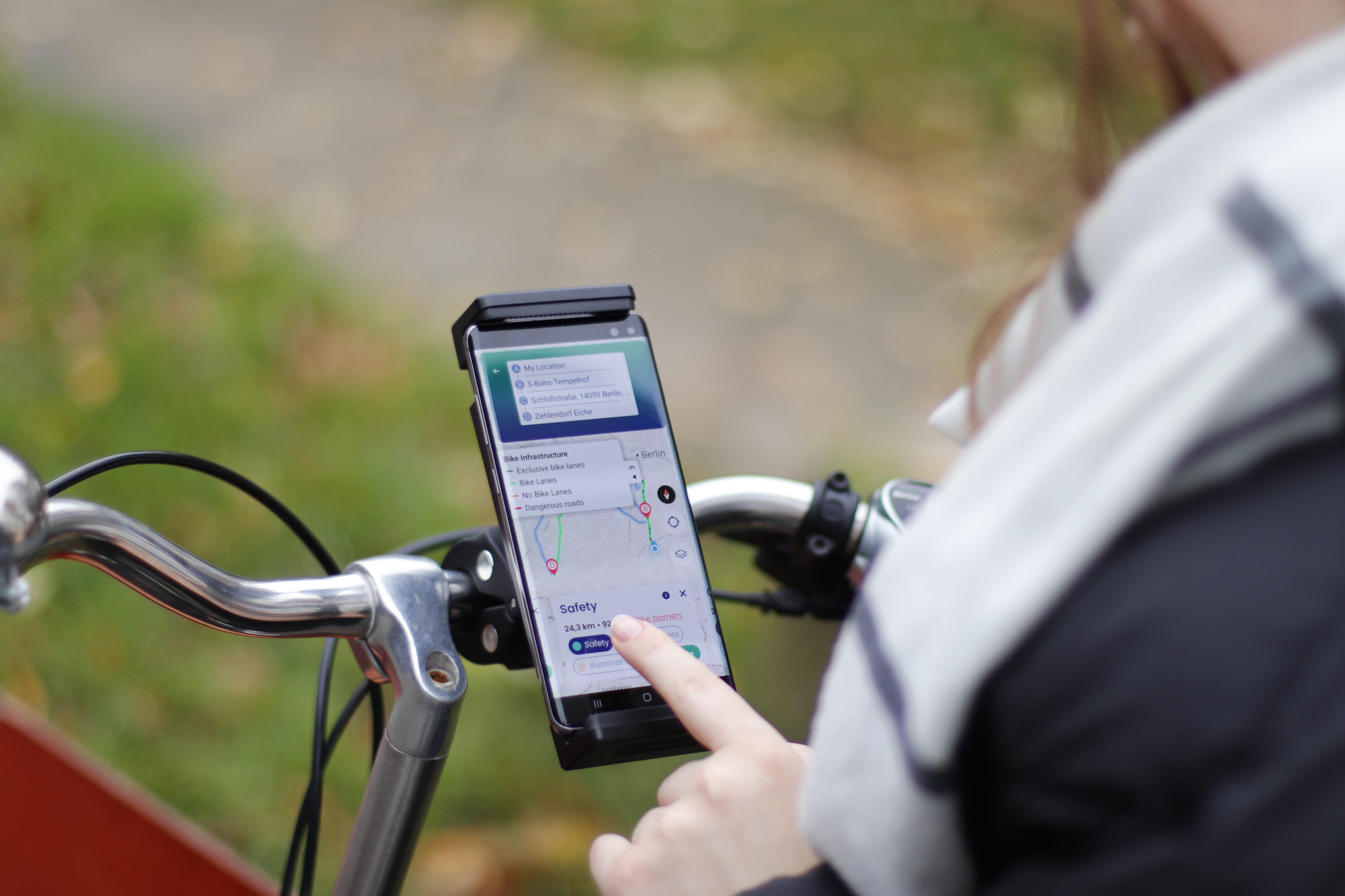 Eine Person nutzt ein Smartphone, das am Fahrradlenker befestigt ist und die App CargoConnect mit einer Karte mit Details zur Fahrradinfrastruktur anzeigt.