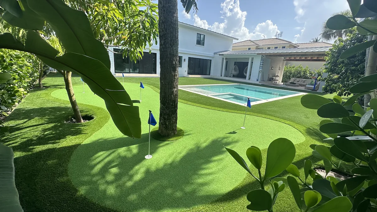 a backyard with a swimming pool and putting green