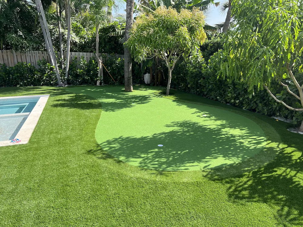 a backyard with artificial grass and a pool