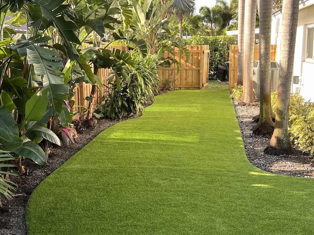 a lush green lawn next to a wooden fence