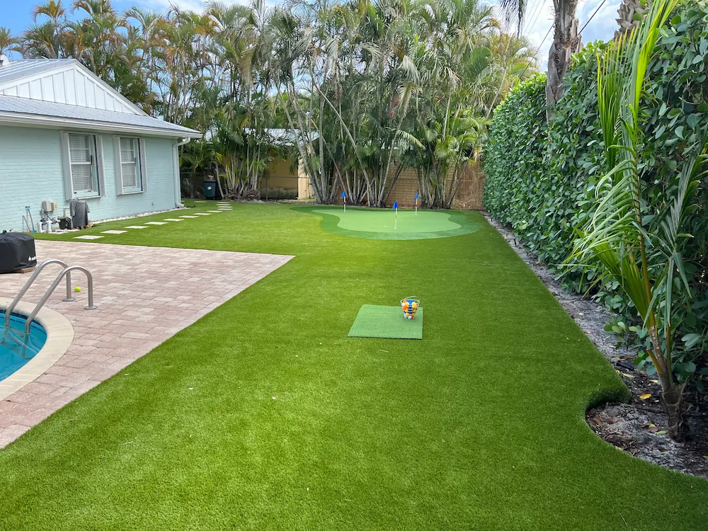 a backyard with artificial grass and a pool