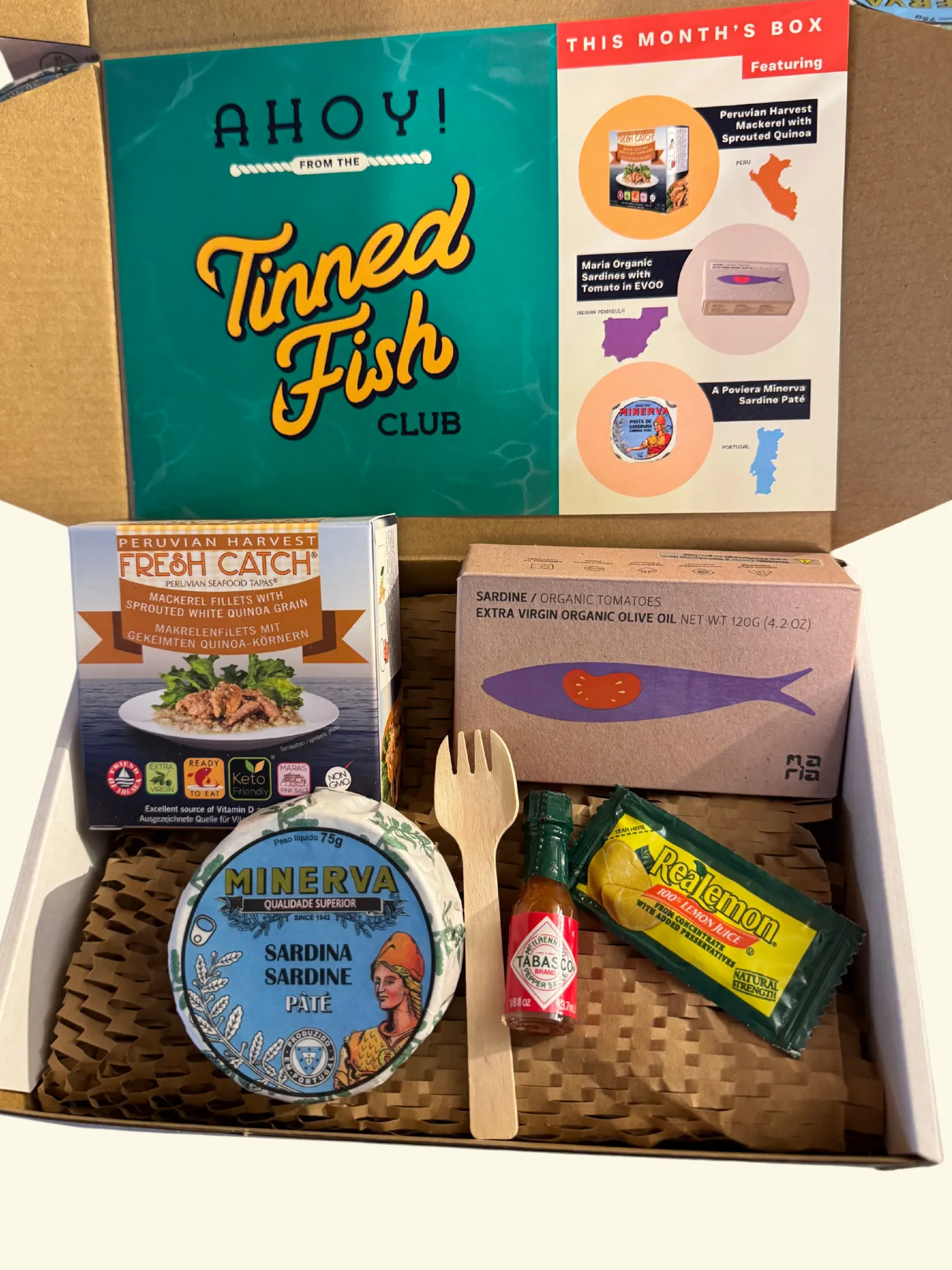 Tinned Fish Club November box with three tins, condiments, and recipe cards