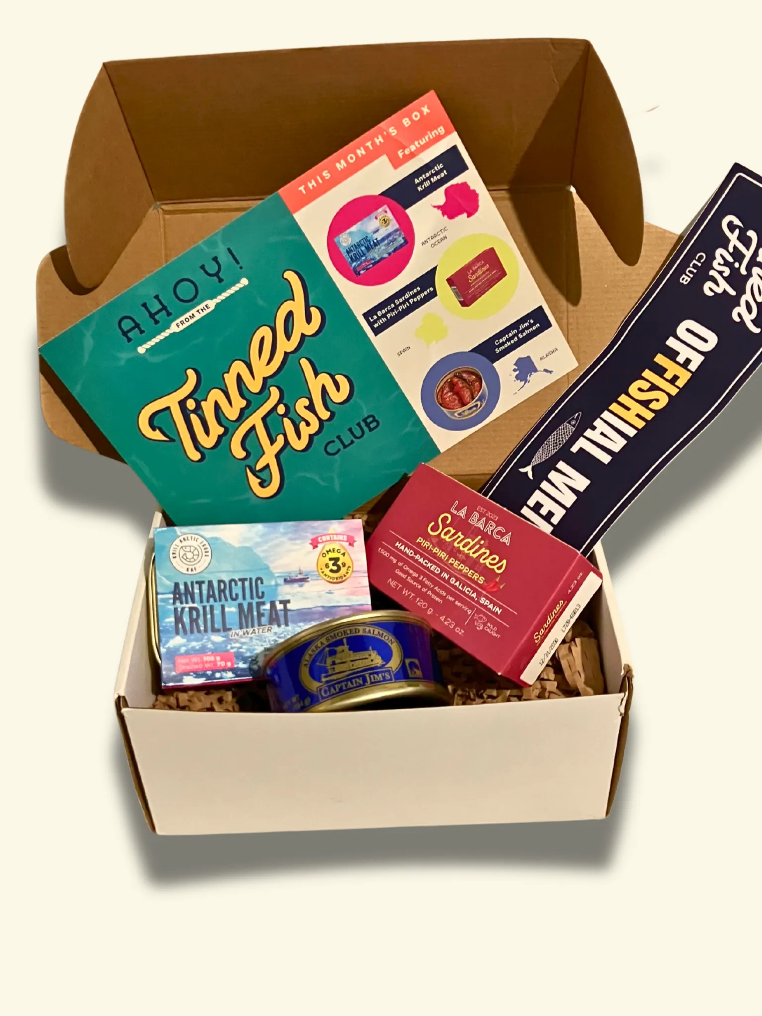Tinned Fish Club August box laid out with tins, snacks, and recipe cards
