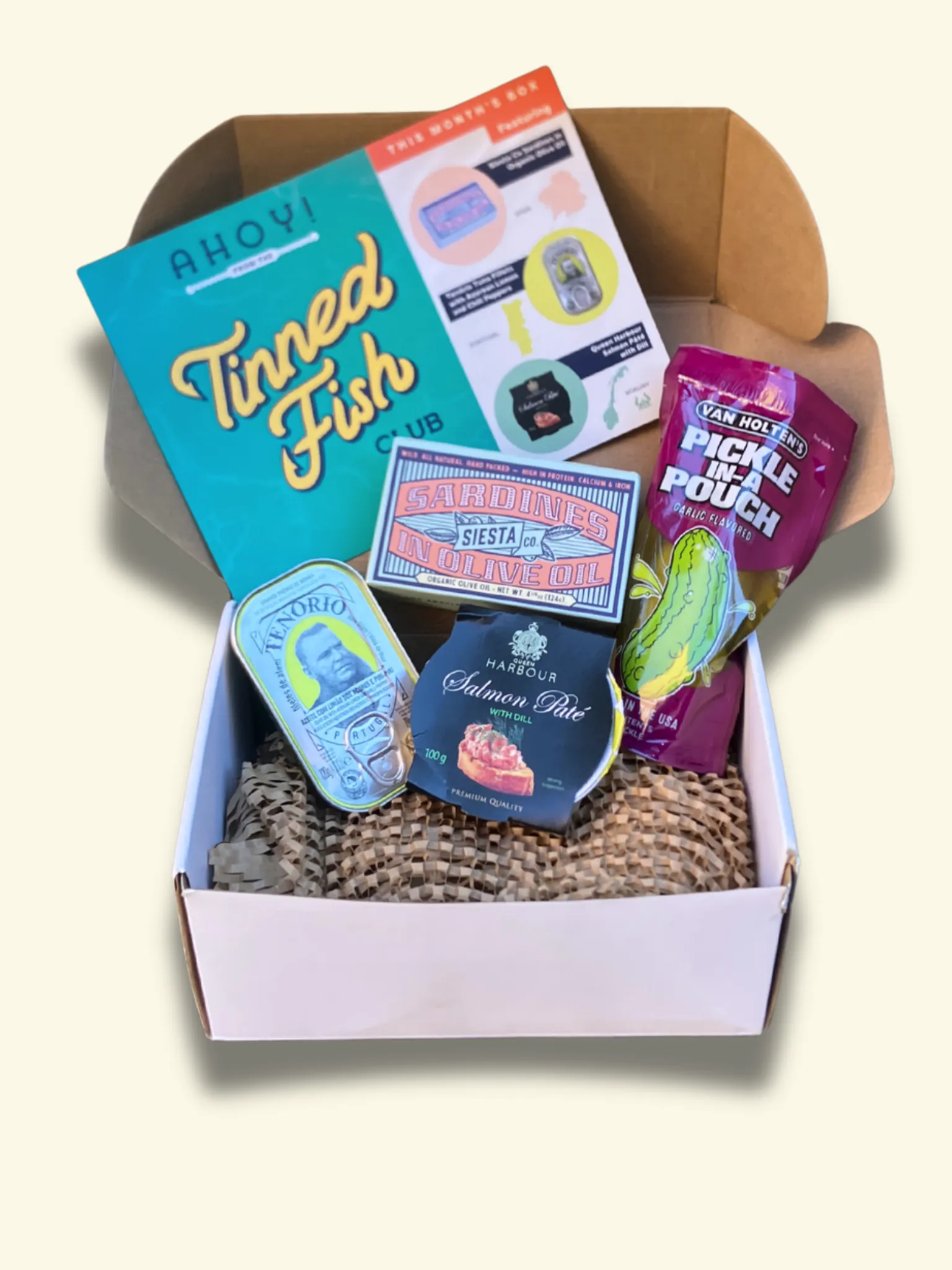 Tinned Fish Club July 2025 box with three tins and paired gourmet snacks