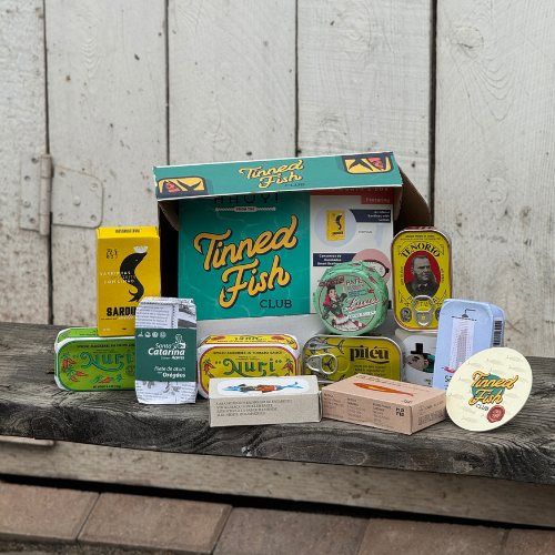 A Tinned Fish Club box surrounded by tins