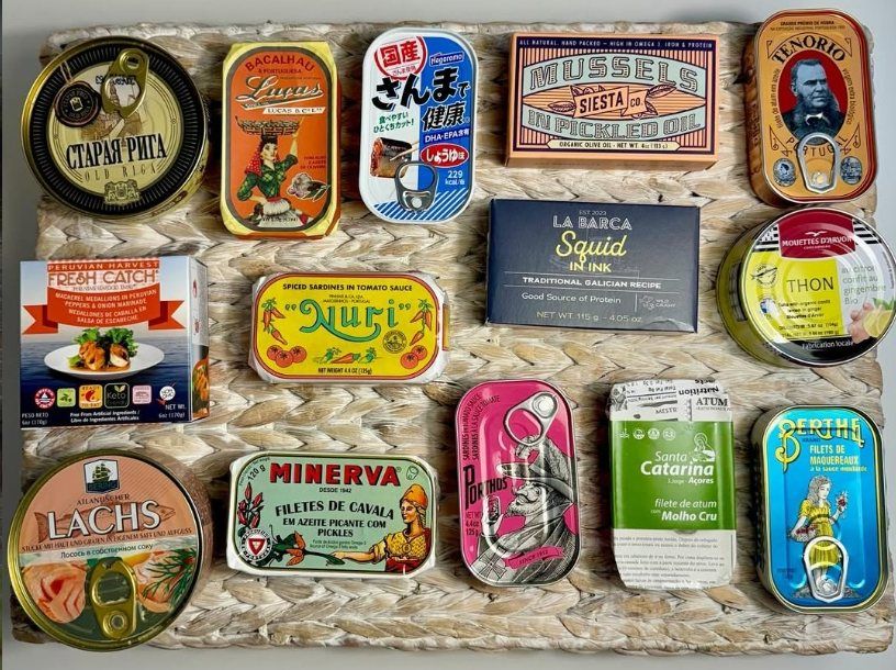 Fifteen colourful tins from Latvia, Portugal, Japan, Spain and beyond laid out on a woven mat