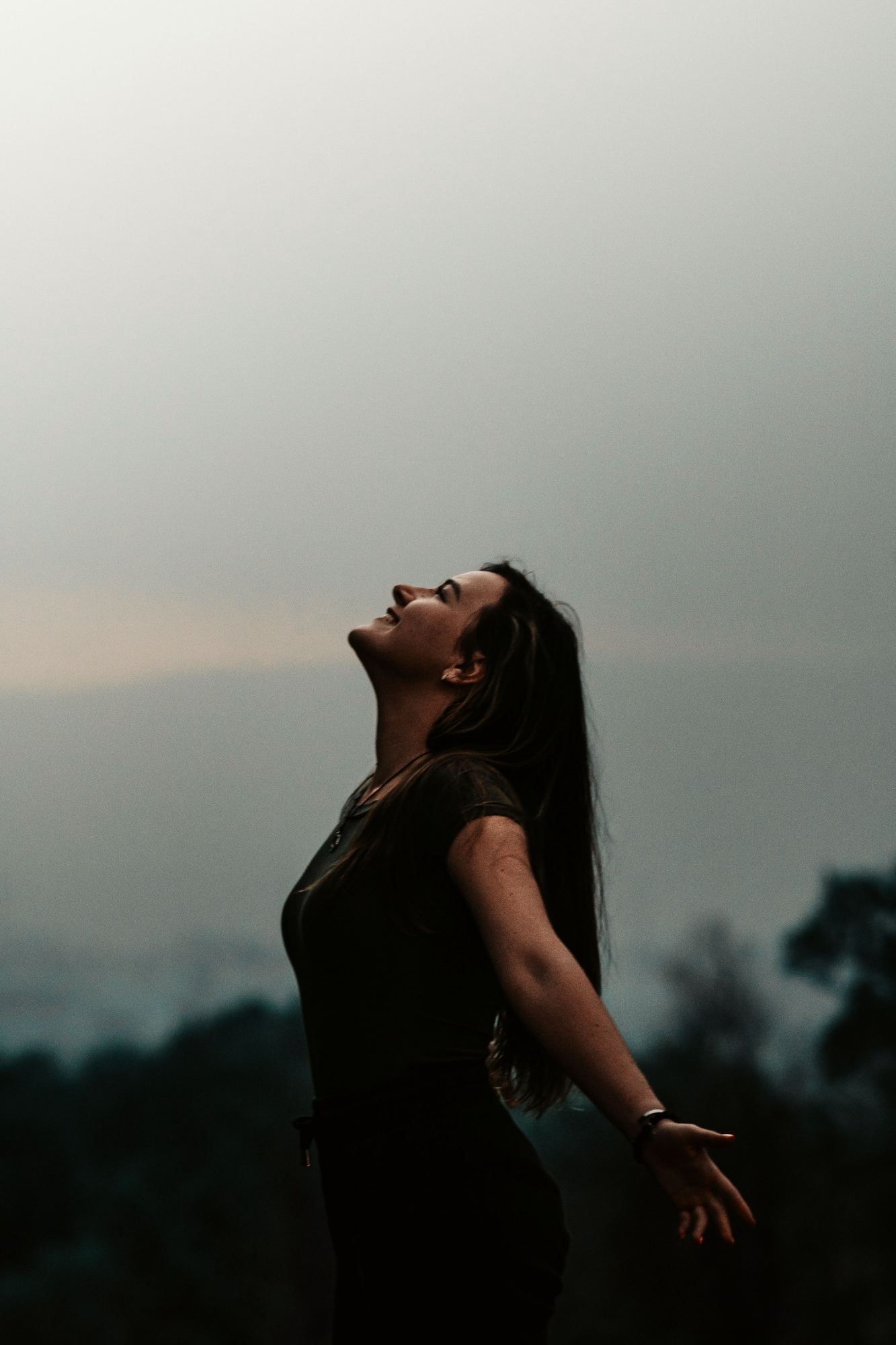 Woman outdoors with her head tilted back and hair blowing in the wind, representing PCOS/PMOS hormonal and metabolic care at Hagen Health & Absolute Aesthetics in Mukilteo, WA.