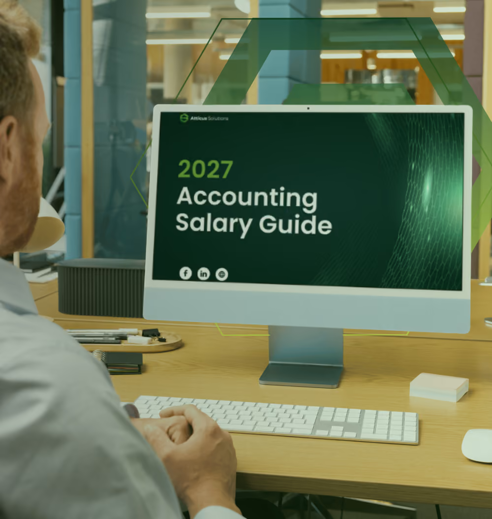 A person holding a tablet displaying the cover of the 2026 Accounting Salary Guide by Atticus Solutions