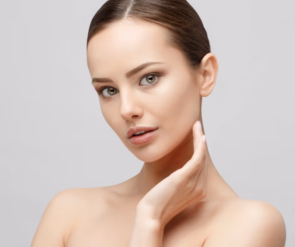 En kvinne med mørkt hår i en pen bolle får en kosmetisk injeksjon på kinnet fra en hanskekledd hånd. Profilen hennes viser markerte linjer.