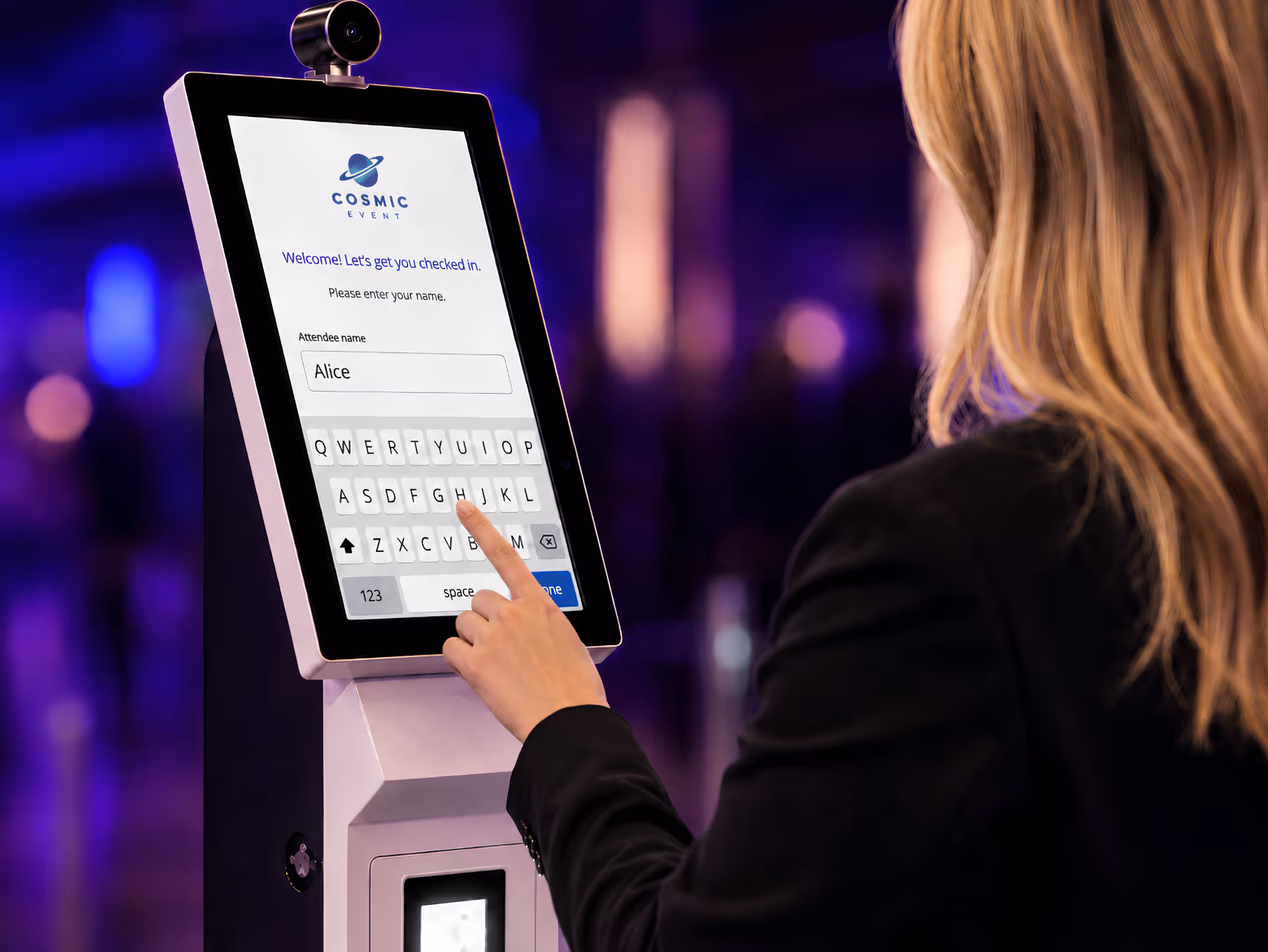 Woman typing the name Alice on a touchscreen check-in kiosk with Cosmic Event logo.