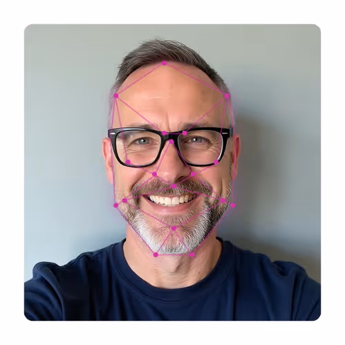 Smiling middle-aged man with glasses and gray beard, with pink facial recognition points on his face.