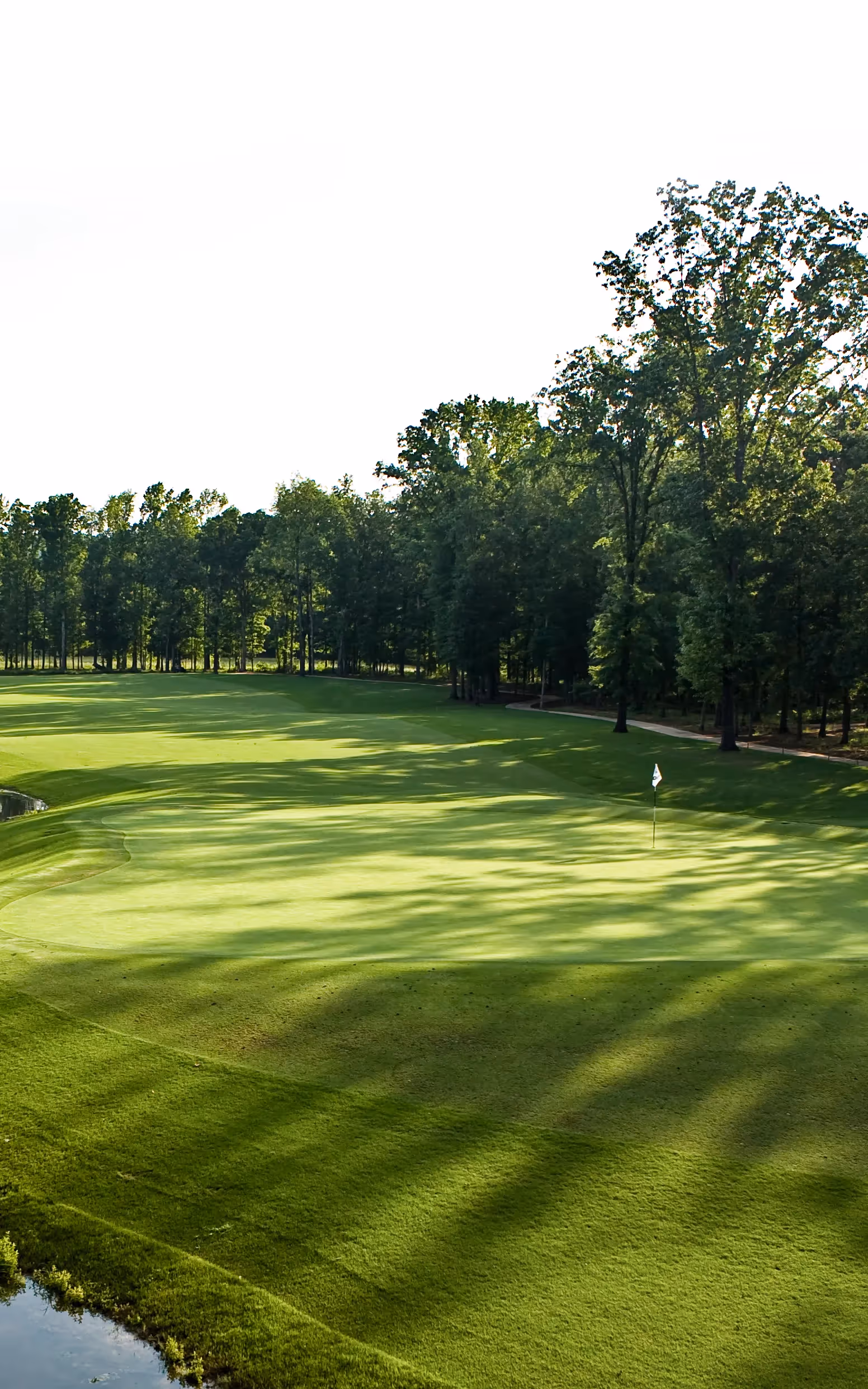 Sky view of open putting green and flag pole with yellow flag