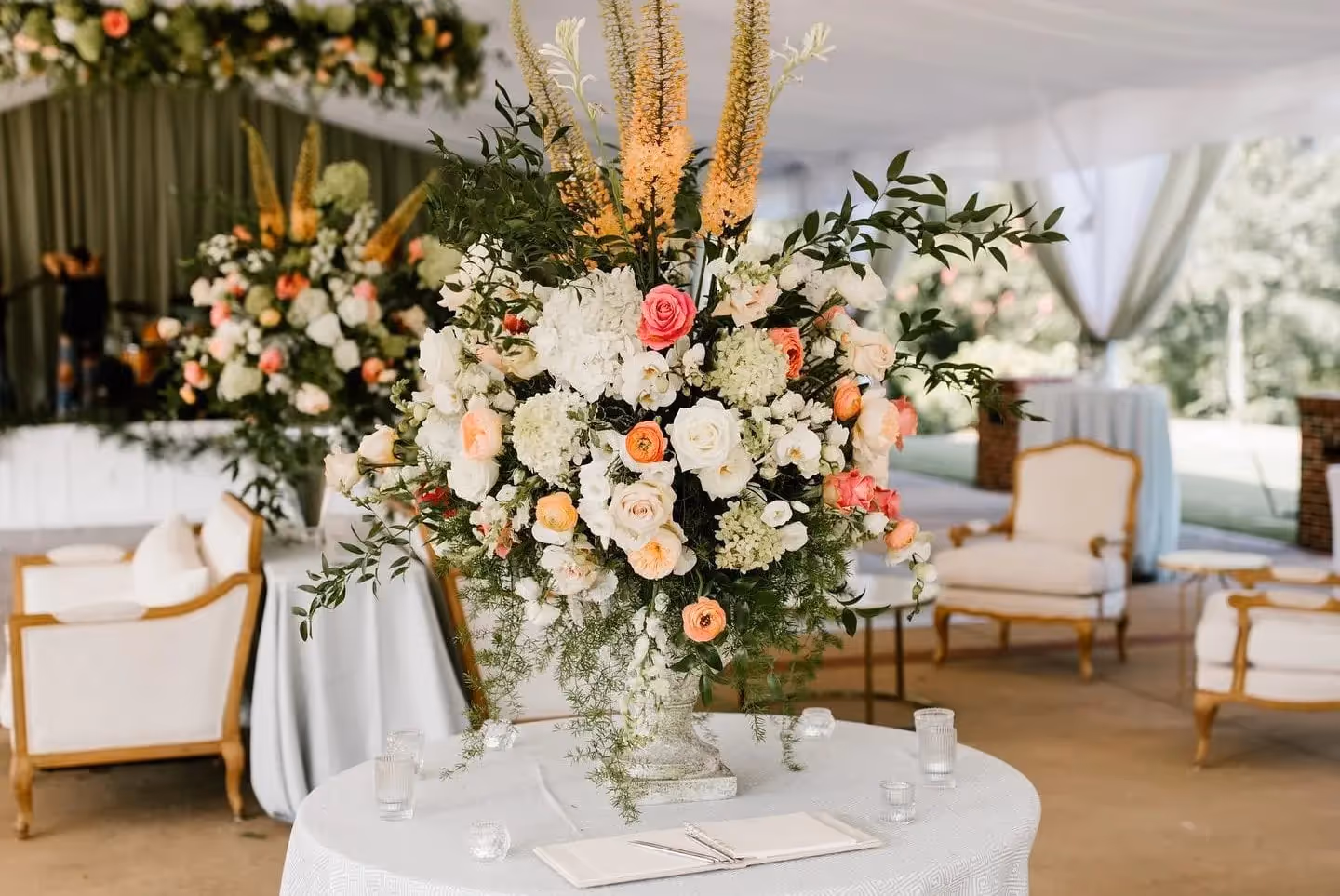 A beautiful floral centerpiece in an outdoor tent reception area.