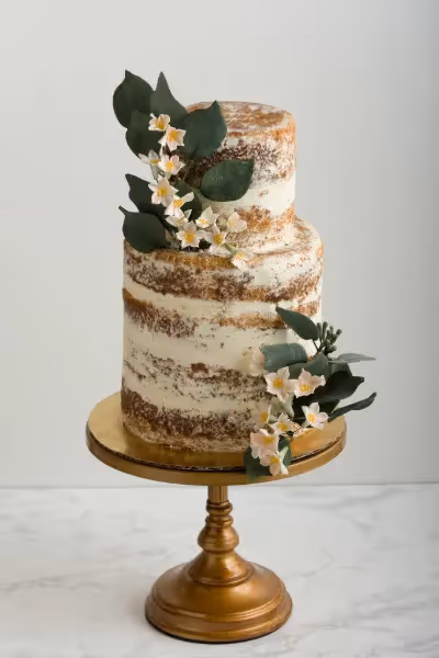 Semi-naked wedding cake with greenery accent.
