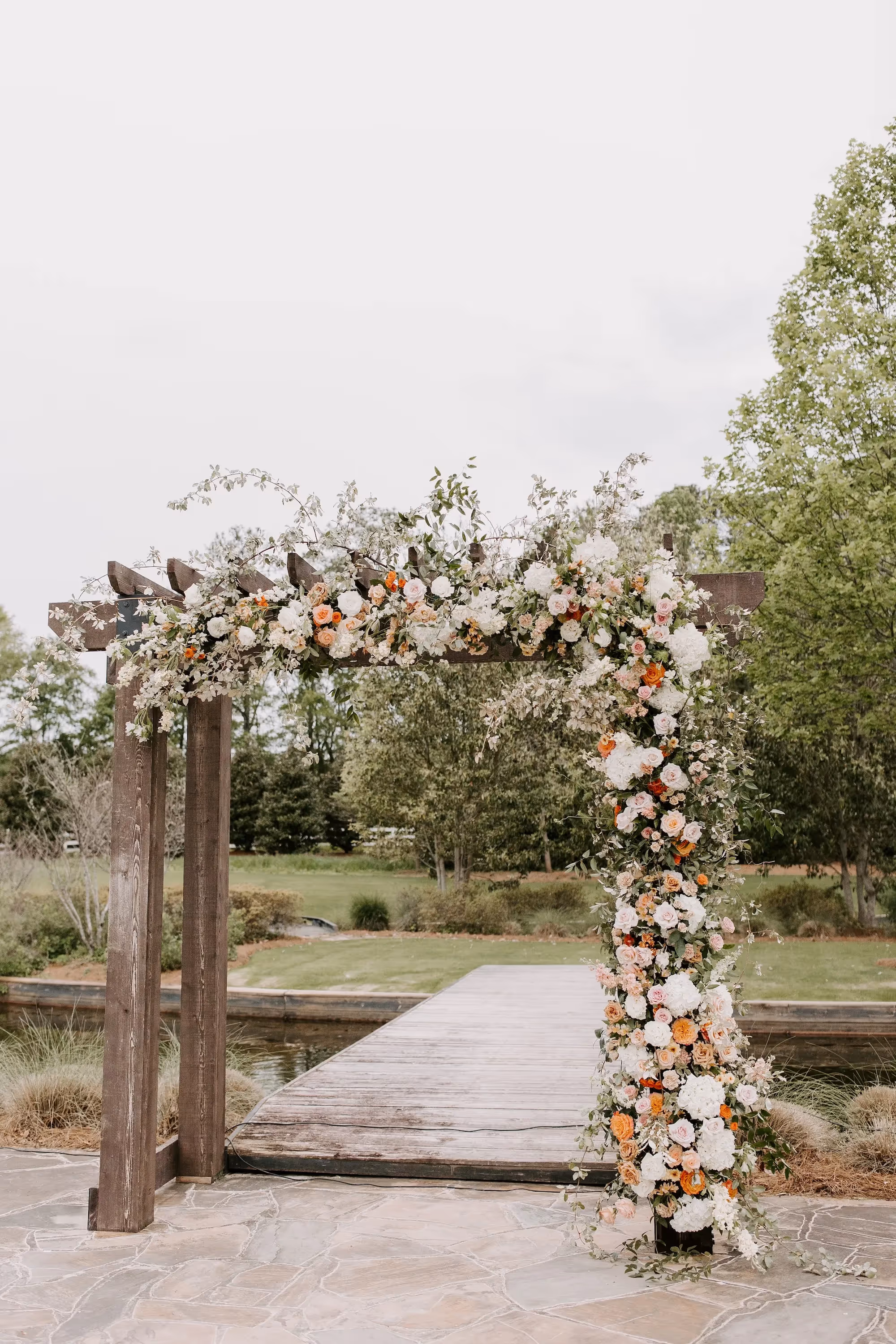 Rustic themed wedding arbor with floral arch, featuring earthy tones.