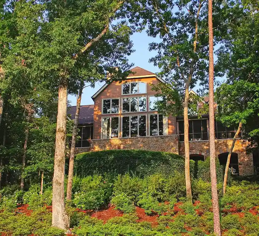 A big house on a small hill with trees.