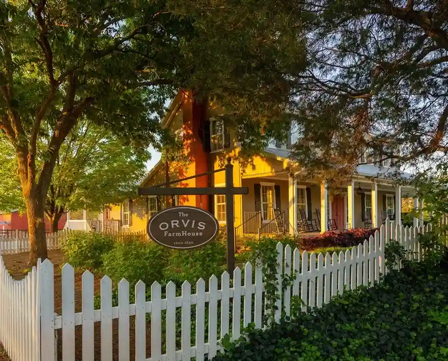 A house surrounded by plants and white picket fence.
