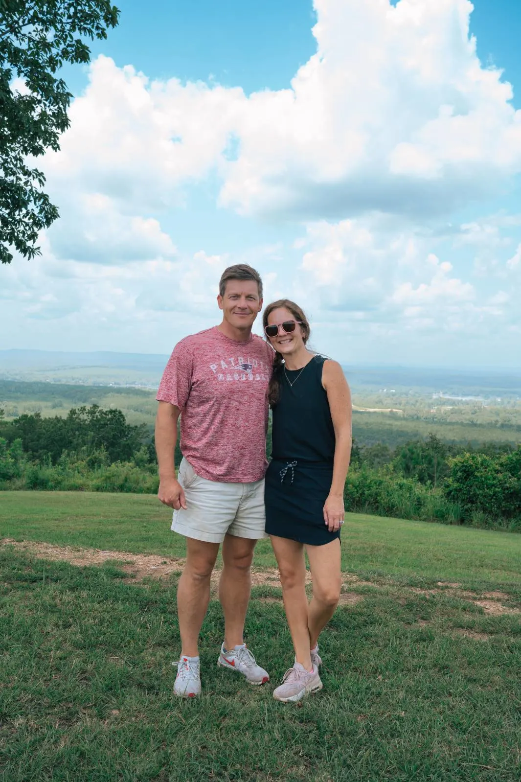 A couple standing with their backs to the camera, gazing out over a pasture.