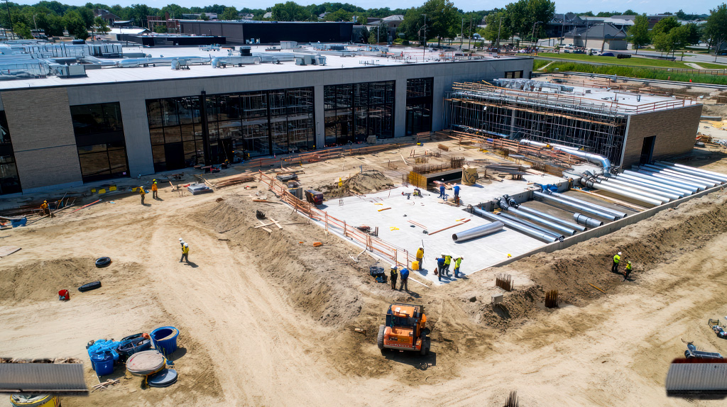 Canteiro de obra organizado com zonas delimitadas, materiais armazenados corretamente e equipes em operação 