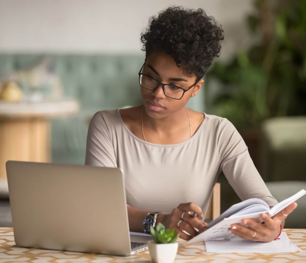 a woman sitting at a table working on a laptop