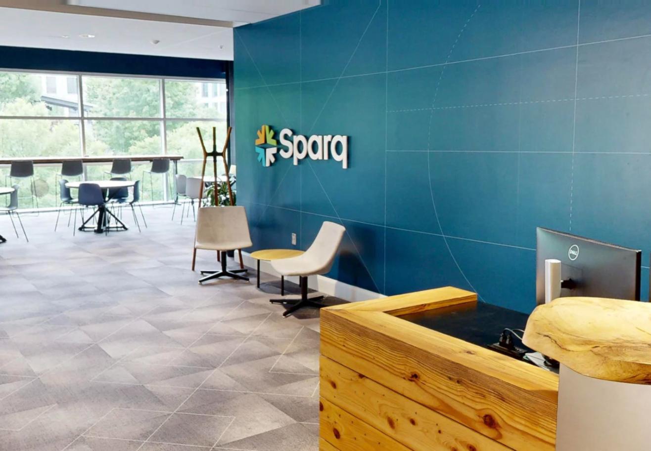 Preview of the Sparq virtual tour: the reception desk and lounge seating in front of the Sparq logo wall