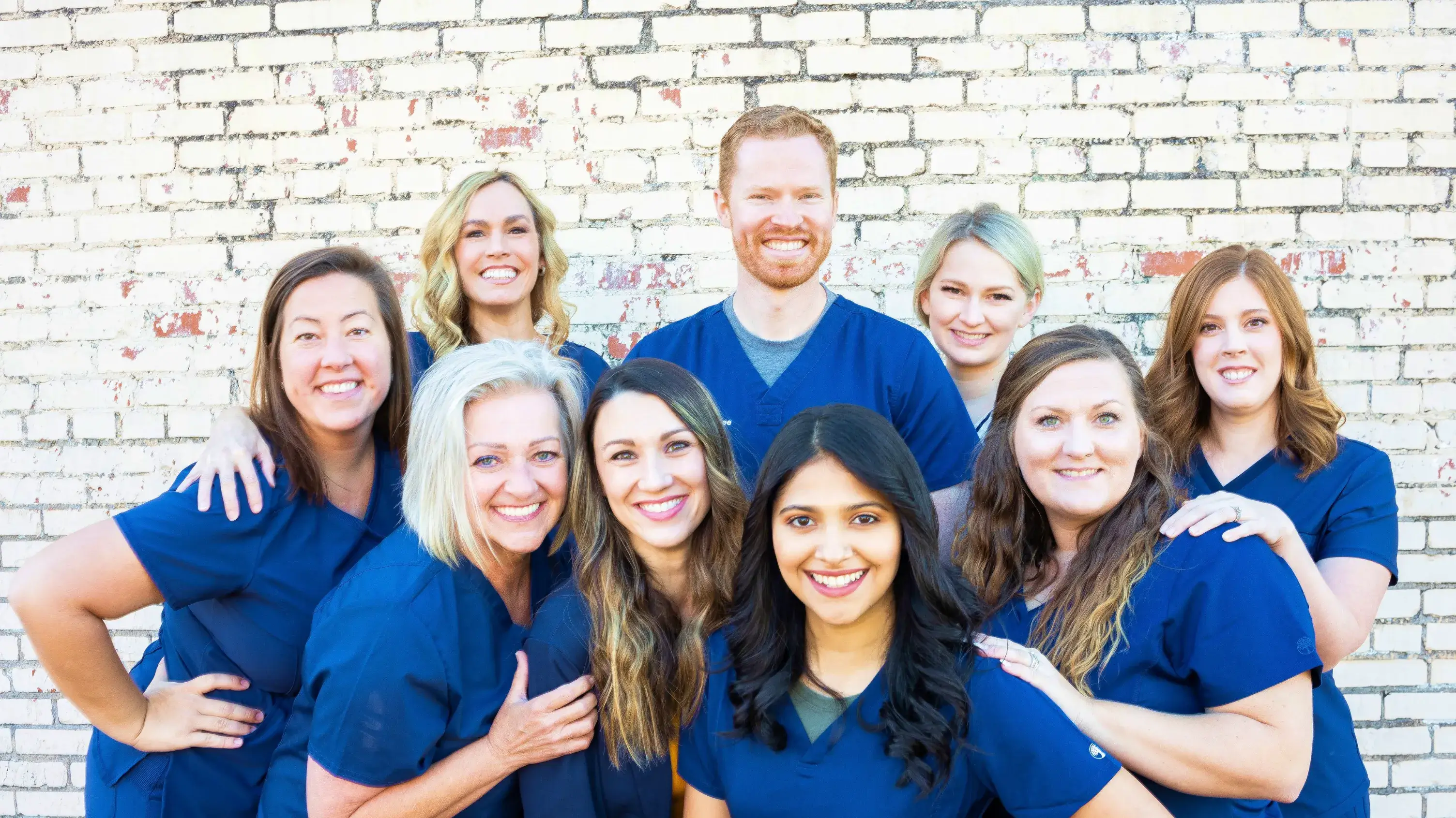 a group of people standing next to each other in front of a brick wall