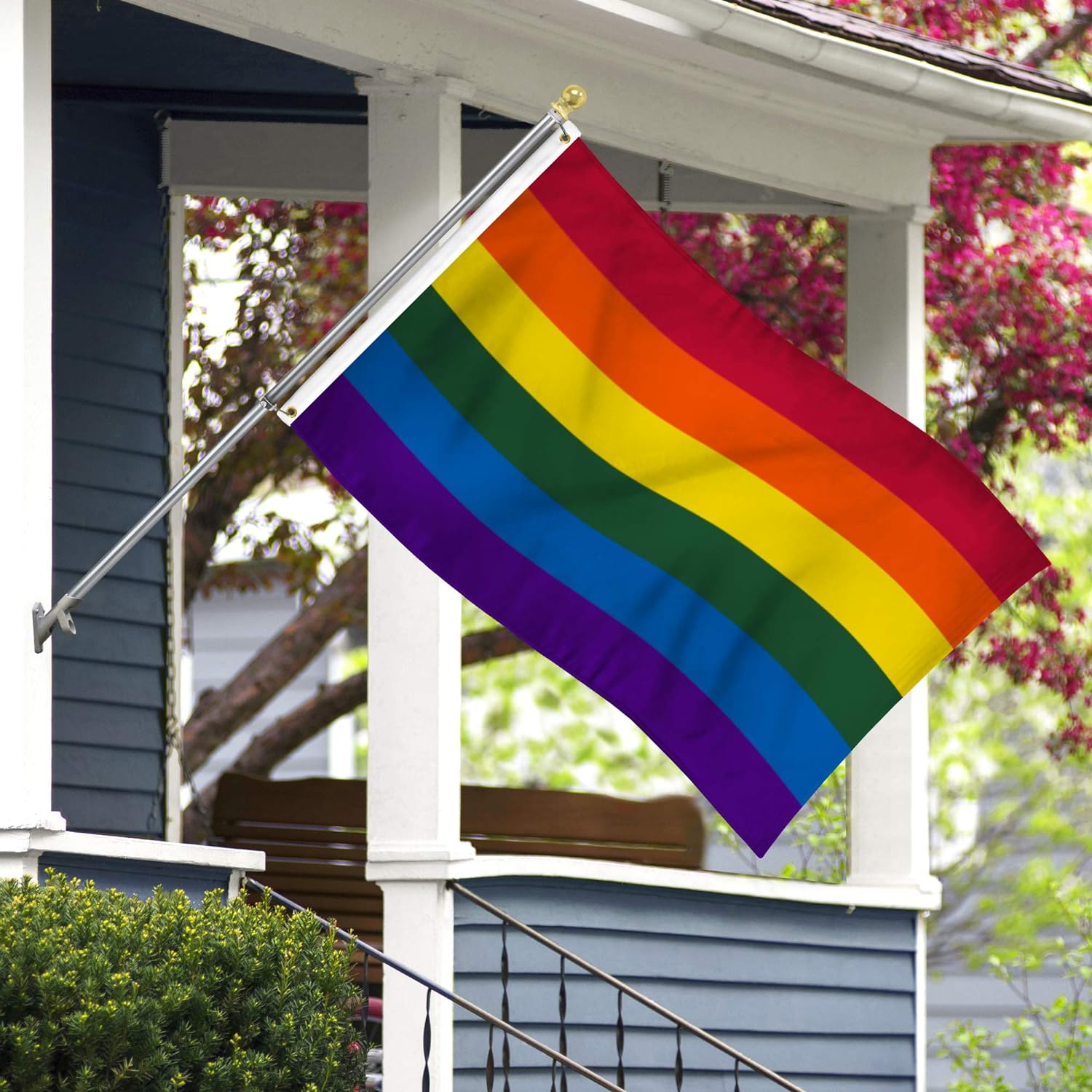 a rainbow pride flag flying in front of a blue house