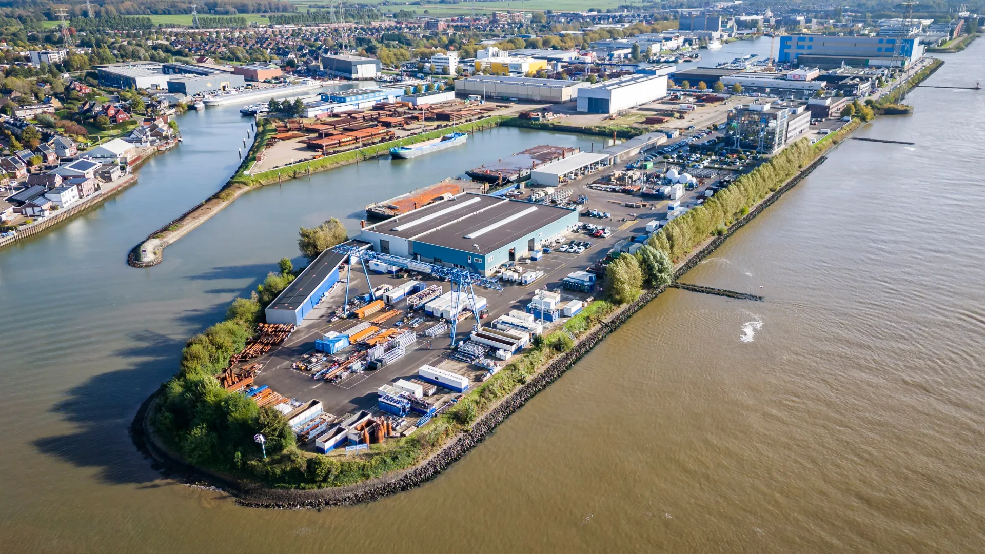 Aerial view of industrial port facility on a peninsula surrounded by water and nearby residential area.